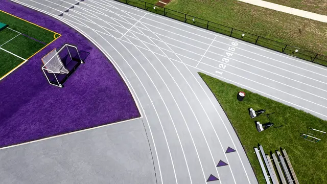 Curved running track lanes beside the purple turf border at Cherry Hill West