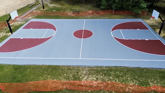 Side view of the gray and red basketball court at Flair Ridge Park