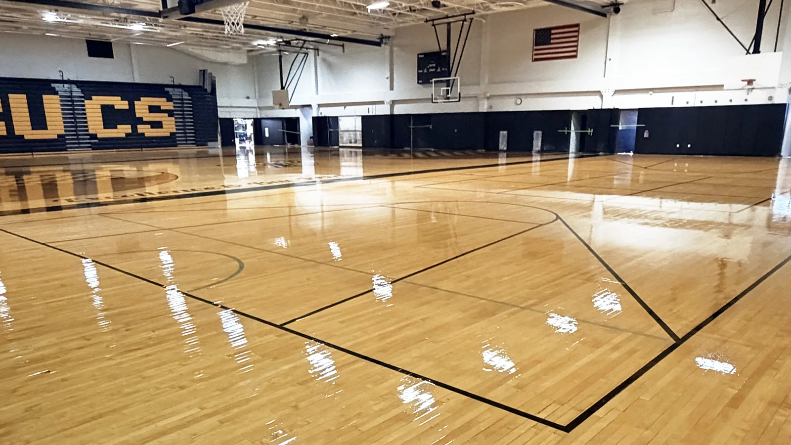 View across the refreshed Interboro basketball court toward the black and gold BUCS bleachers